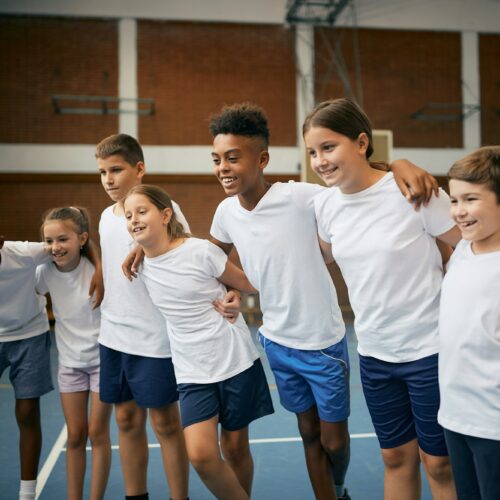 Multi-ethnic group of happy school children having PE class at at school gym.